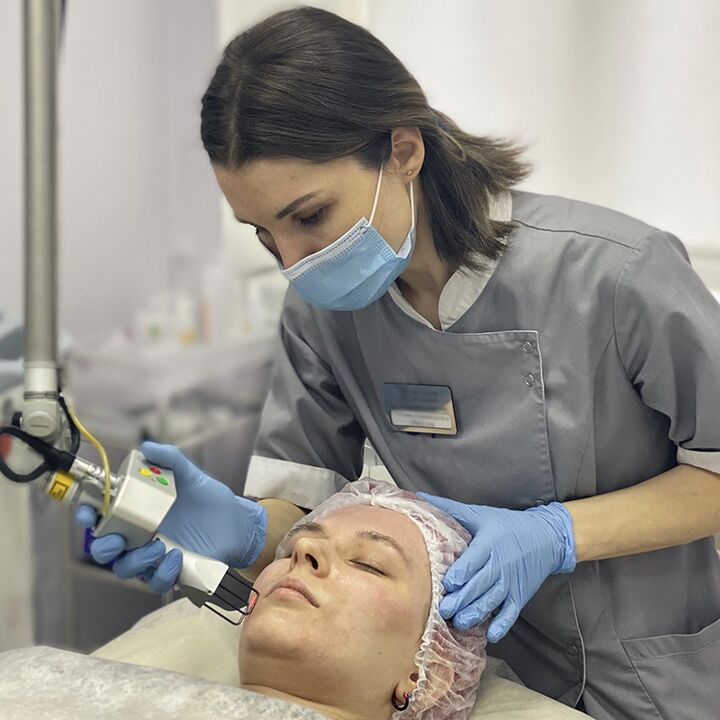 A beautician performs laser fractional facial skin rejuvenation